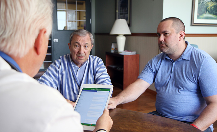 Two men sitting at a table talk with a VITAS physician