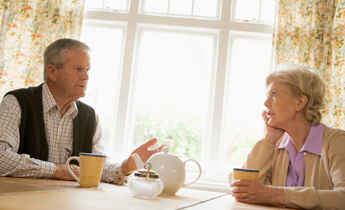 A couple talks over a cup of tea at the kitchen table