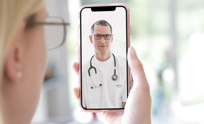 A woman talks with a physician on a videoconference via smartphone