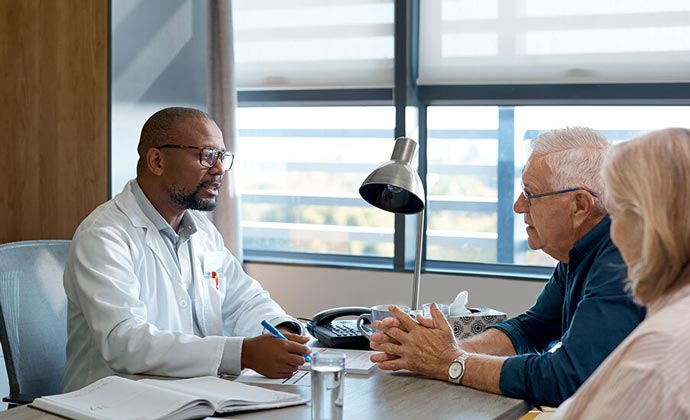 A physician discusses treatment options with an older couple.