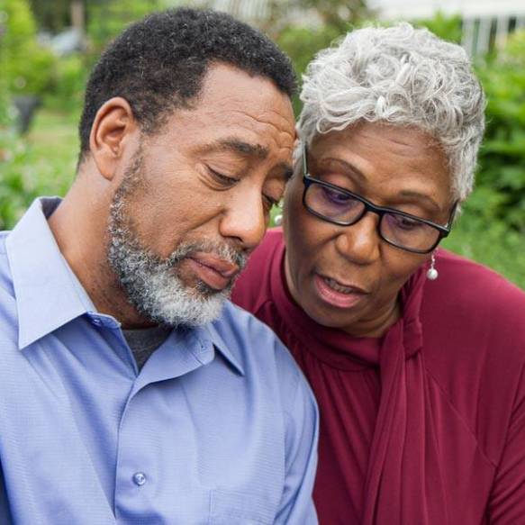 A woman wraps her arm around the shoulder of a crying man